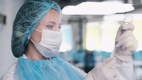 Medic in a protective face mask draws a vaccine into a syringe. Corona virus Stock Footage 139256265
