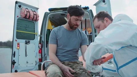Medic provides first aid and rewinds his hand with a bandage to wounded soldiers Stock Footage 190594355