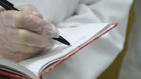 Medic in rubber gloves writes in notebook Video stock 149353487