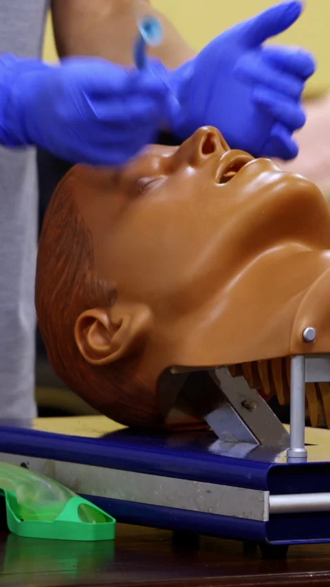 Medic shows how to insert oxygen tube in nose of a medical dummy. Stock Footage 274188459