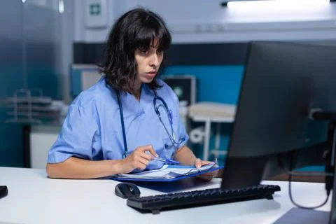 Medical assistant analyzing documents and files on monitor Stock Photos