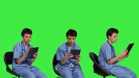 Medical assistant browsing internet on tablet while she sits down in a chair Foto stock