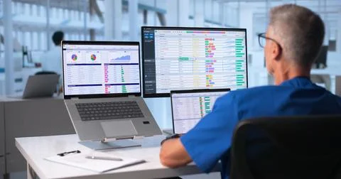 Medical Coder Carefully Checks Billing Codes On Laptop At Hospital Office. Stock Photos