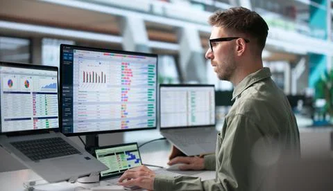Medical Coder Checks Billing Codes On Laptop In Busy Office Environment. Stock Photos