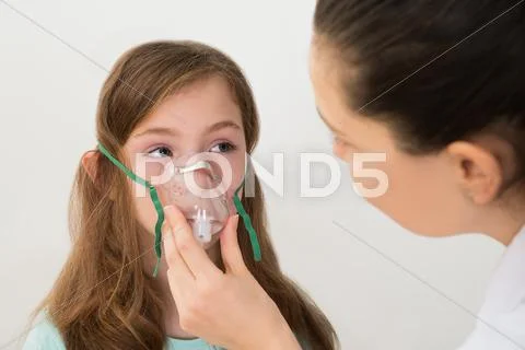 Medical Doctor Holding Inhaler Mask For Girl Breathing Stock Photos