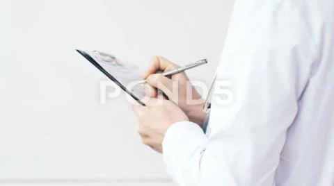Medical doctor writing a prescription on a clipboard in the hospital. Stock Photos