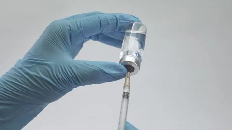 Medical gloves holding a syringe while drawing liquid from a glass vaccine vial 스톡 동영상 322165633