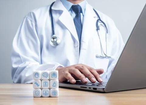 Medical icon blocks stack beside doctor works on laptop. Telemedicine, diag.. Stock Photos