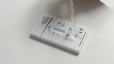 Medical lab technician dropping sample on hCG rapid pregnancy test cassette Stock Footage 337908276