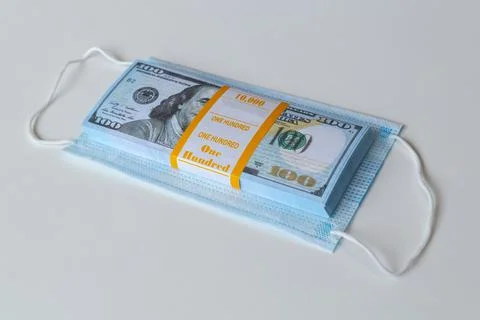 A medical mask and a stack of 100 dollars bills as a symbol of higher prices Stock-Fotos