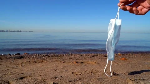 Medical mask in hand develops in the wind against the background of the sea. Stock Footage 131274520