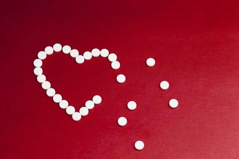 Medical medicines tablets stacked on a red background in the shape of a heart Stockfoto's