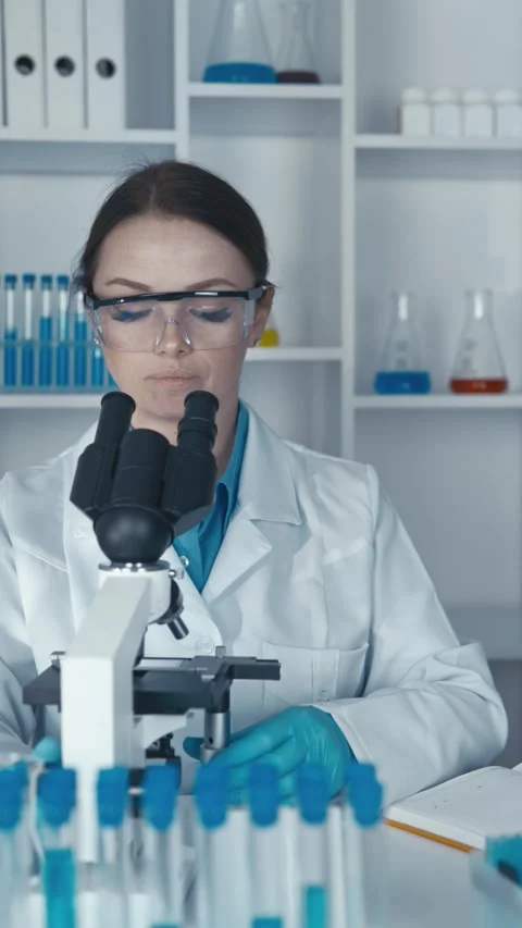 A medical microbiologist with a microscope conducts research on bacteria and Stock Footage 266563353