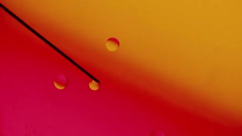 Medical needle makes drops of different sizes on a red-yellow gradient surface. 스톡 동영상 303059522