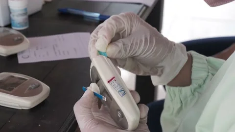 Medical officer inserting disposable test strip into a blood sugar meter Stock Footage 169580029