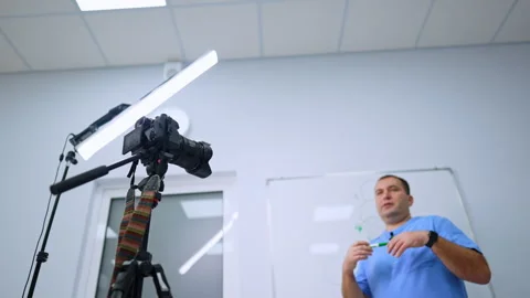 Medical presenter gesturing toward a camera under studio lighting. A low Stock Footage 346615081