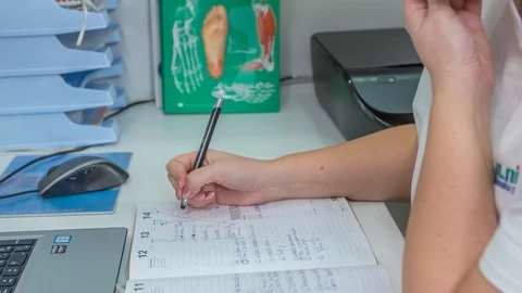 A medical professional  writing down the notes on paper while talking over Stock Footage 122373260