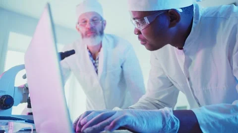 Medical research team analyzing data on laptop and using microscope Видео 304889893