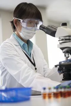 Medical researcher in PPE using microscope in laboratory Foto stock