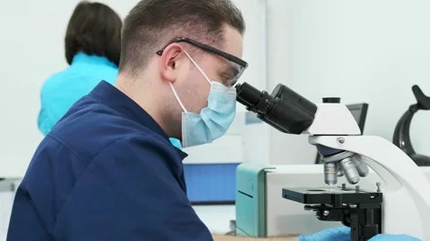 A medical scientist conducts experiments with a microscope Видео 269350104