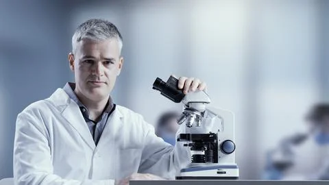 Medical scientist posing with a microscope Stock Photos