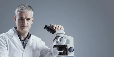 Medical scientist posing with a microscope Stock Photos