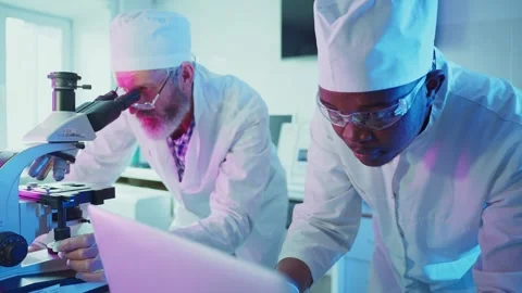 Medical scientists analyzing sample under microscope in laboratory Stock Footage 306589005