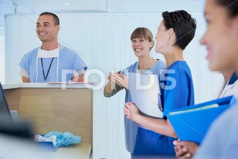 Medical Staff Chatting At Nurses Station In Hospital