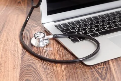 Medical stethoscope with a modern laptop computer on wooden background 스톡 사진