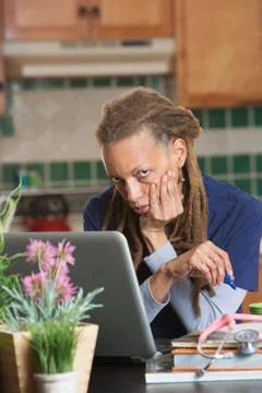 Medical student sits at kitchen table with books and laptop Stock Photos