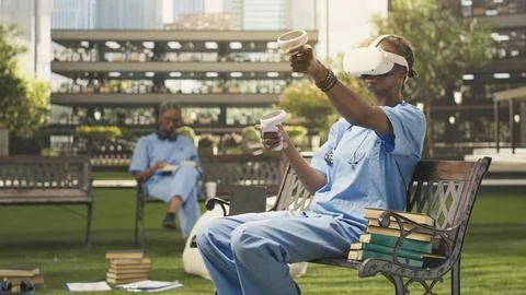 Medical student using VR controllers and headset on wooden bench Stock Photos