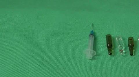Medical syringes and vials on green background Video stock 59120947