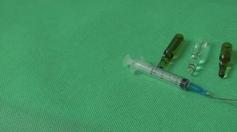 Medical syringes and vials on green background Video stock 59121645