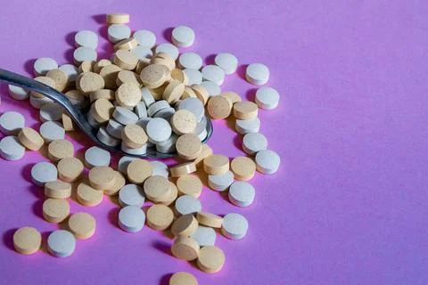 Medical tablets of round shape fall from a spoon on background. mock up Stock Photos