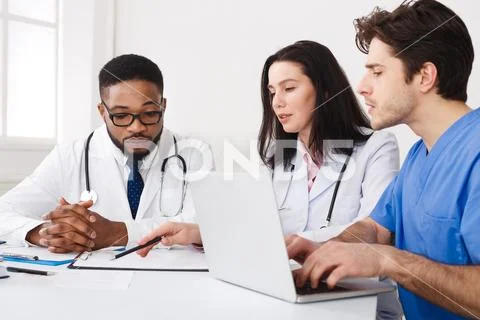 Medical Team Discussing Reports, Using Laptop At Meeting Stock Photos