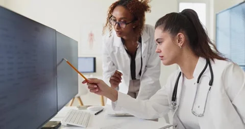 Medical team of doctors analyzing patient records on computer monitors in clinic Stock Footage 344405193