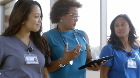 Medical team walking in hospital corridor using digital tablet Stock Footage