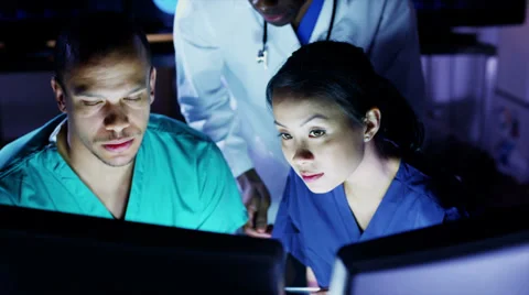 Medical team working late at a computer and discussing what they see on screen Stock Footage