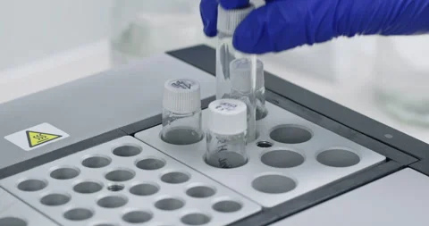 Medical technologist insert glass flasks into testing device Stockbeeldmateriaal 274573516