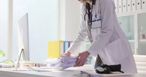 Medical worker carries large stack of paperwork to desk Stock Footage 309034034