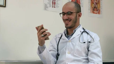 Medical worker checking his phone and laughing at something Stock Footage 72396665