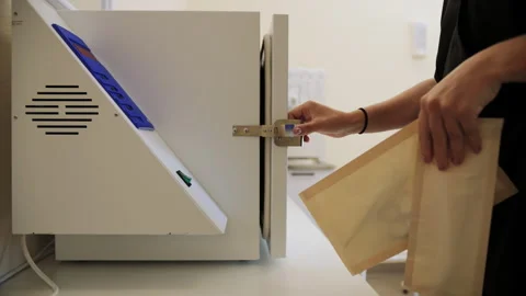 Medical Worker Removing Sterilized Instruments from Autoclave Stock Footage 285032184