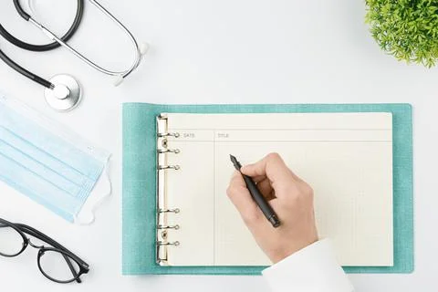 Medical worker at table write in notebook top view Stock Photos