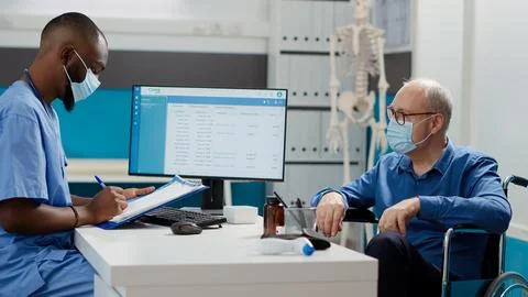 Medical worker taking notes at consultation with senior man Foto stock