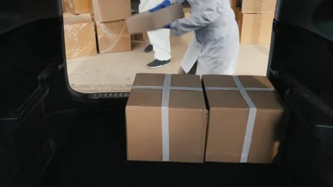 Medical workers in protective suits loading medicine cardboard boxes into c.. Stock Footage 334791598