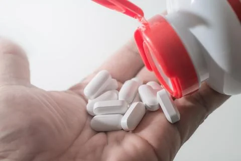 Medication bottle open being poured into hand Stock Photos