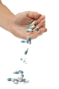 Medication capsules falling from a hand isolated silhouette on white background. Stock Photos