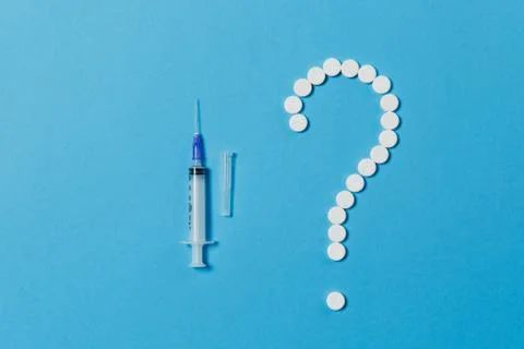 Medication white round tablets arranged in question mark shape isolated on blue Stock Photos