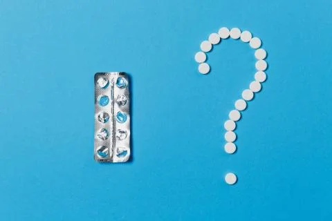 Medication white round tablets arranged in question mark shape isolated on blue Stock Photos