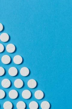 Medication white round tablets arranged in form of triangle isolated on blue Stock Photos